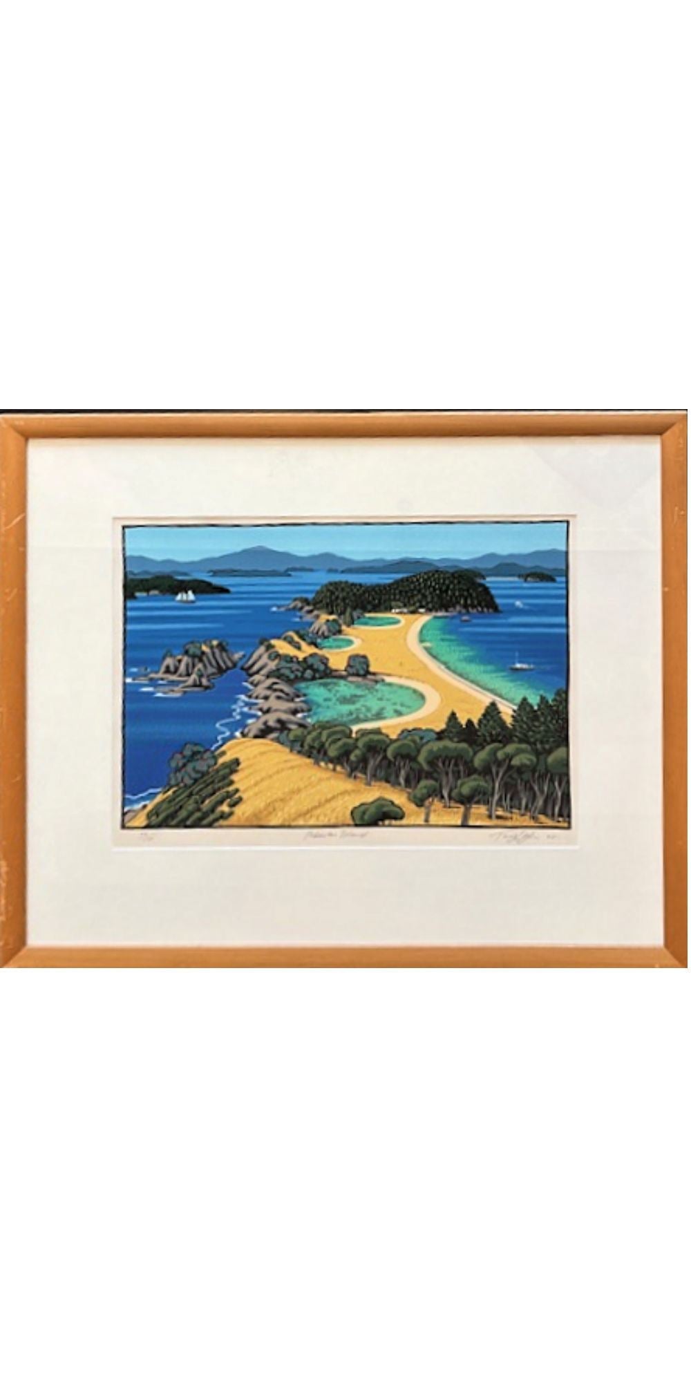 Framed artwork of a coastal landscape with a beach and ocean.